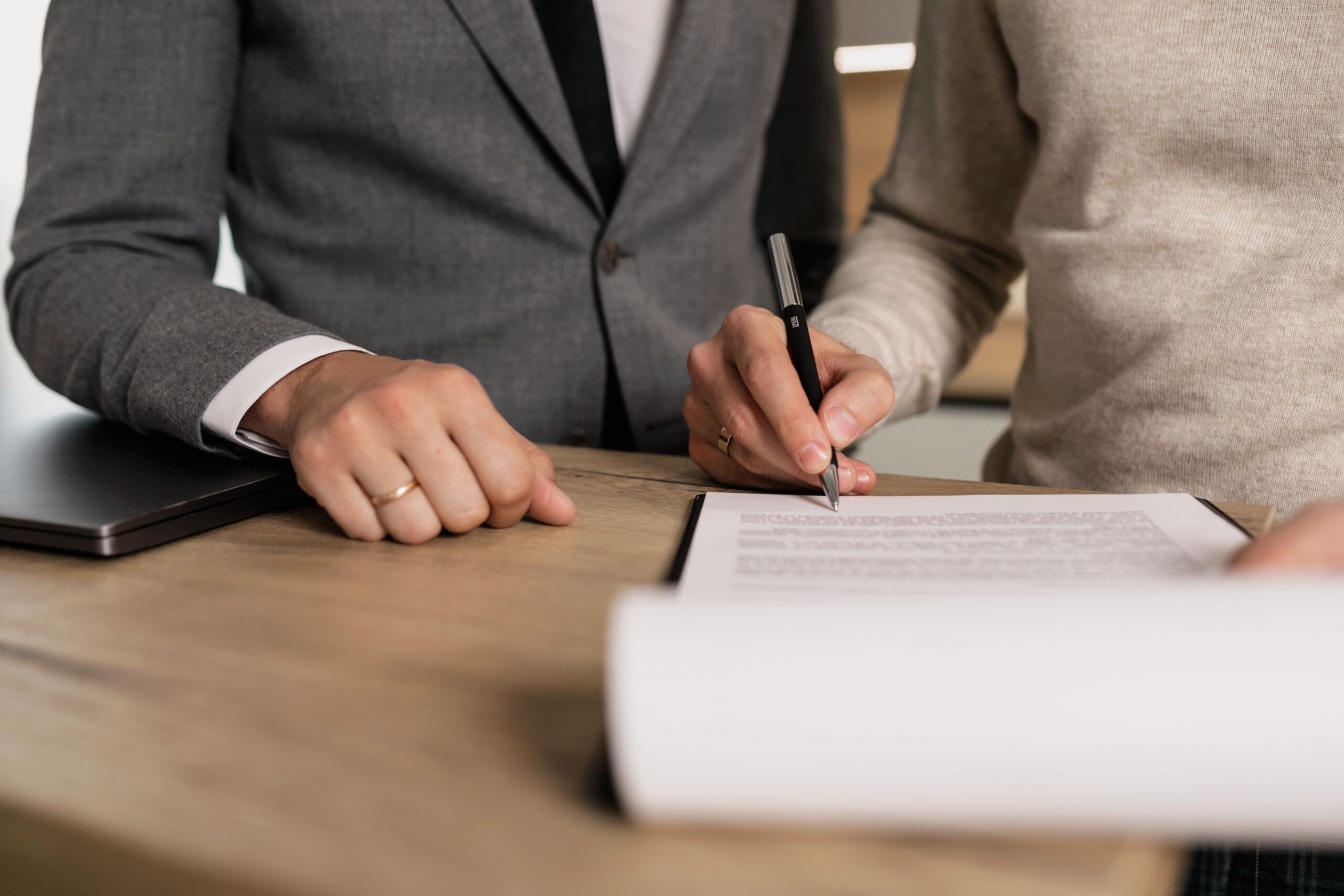 Two people signing a property title document together at a desk